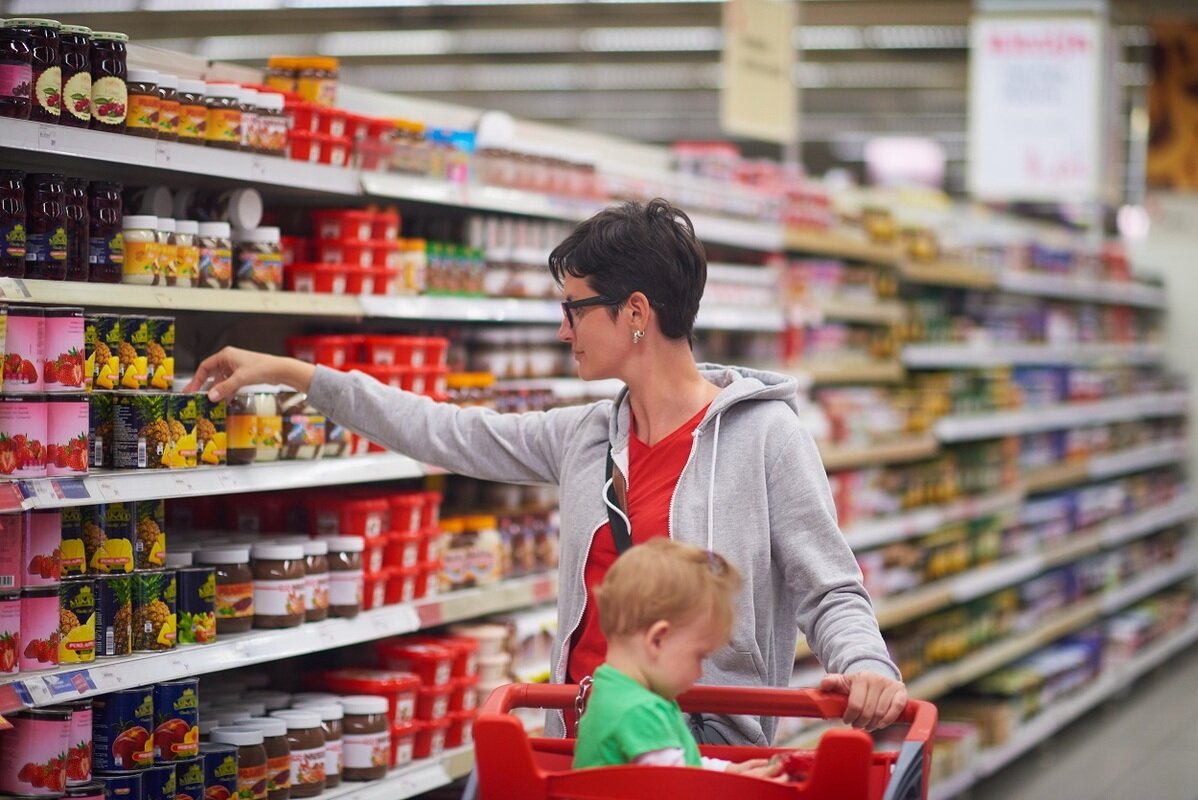 woman grocery shopping with child in cart