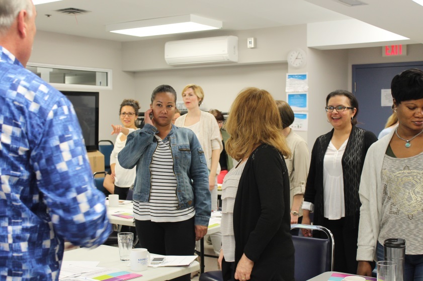 People standing in a room together, listening to one person talk