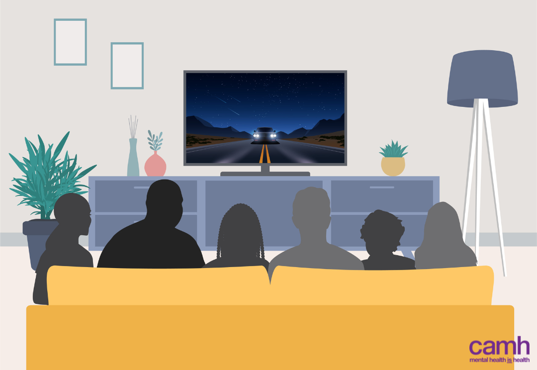 John watching television with his five other housemates on a couch in his group home.